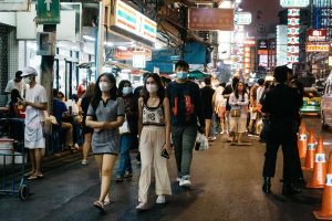 Crowds walking through a busy Bangkok street at night