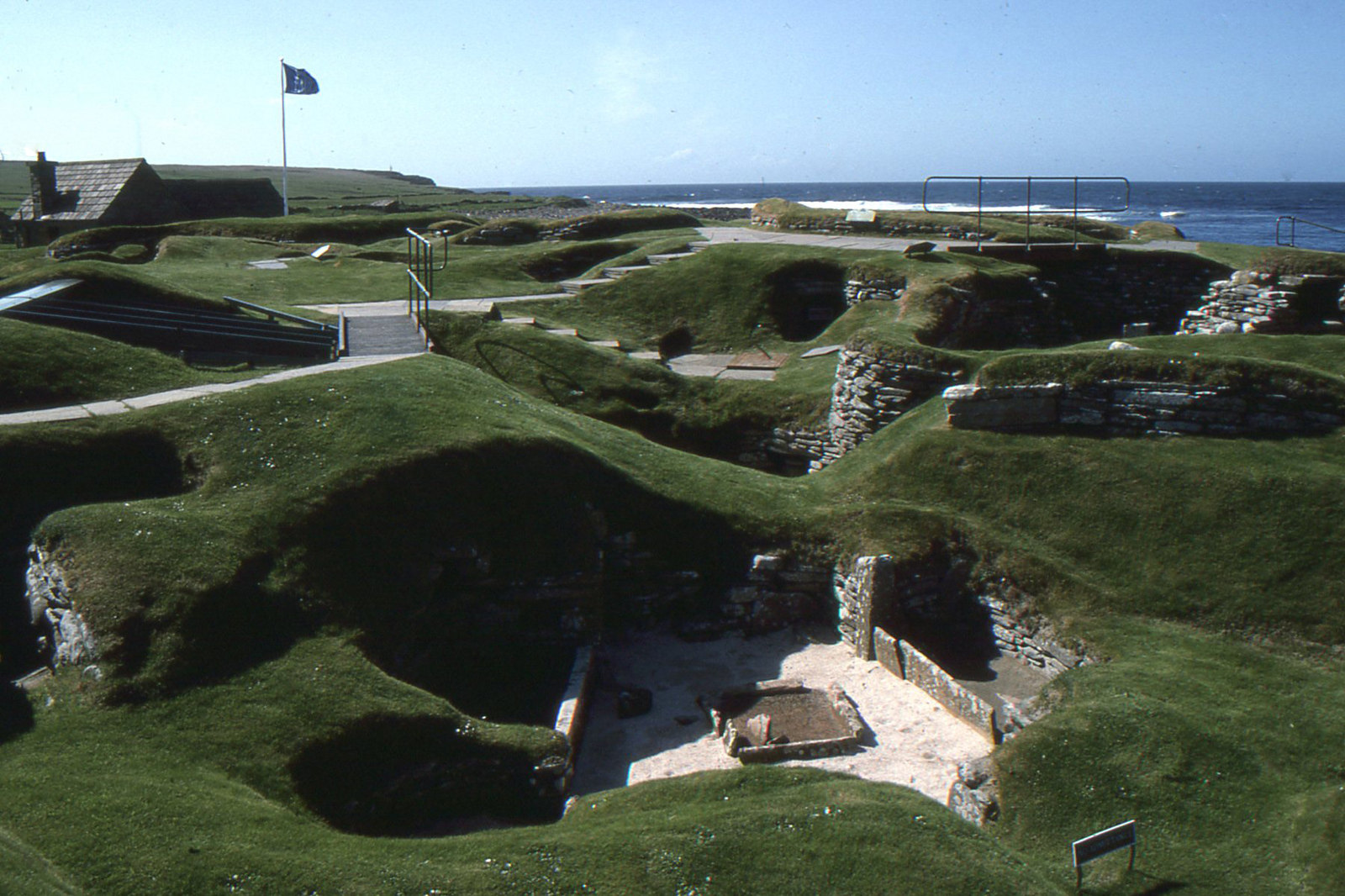 Inside one of the houses, the stone furniture survives: a central hearth, wall beds, and the famous stone “dresser” against the back wall.