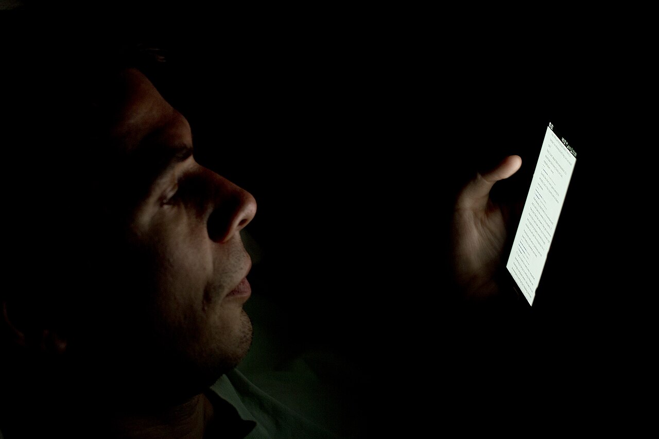 A person looking at a smartphone in the dark