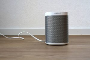 A modern wireless smart speaker on a shelf