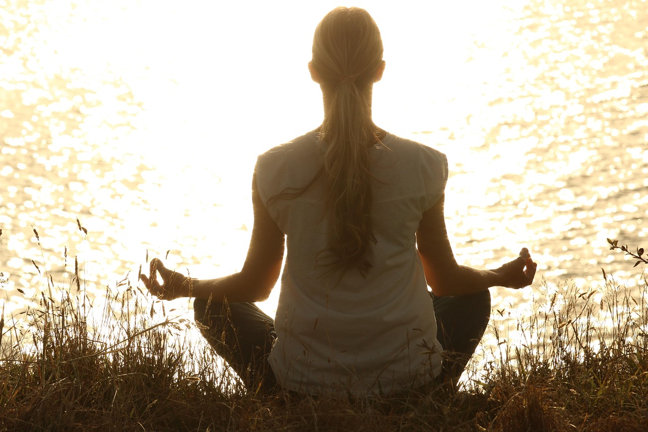 A person meditating in silhouette at sunset