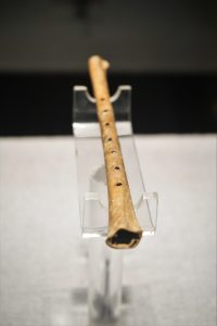 A Jiahu bone flute shown upright, its finger holes still clearly visible