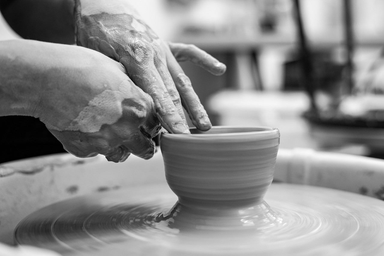 Hands shaping clay pottery