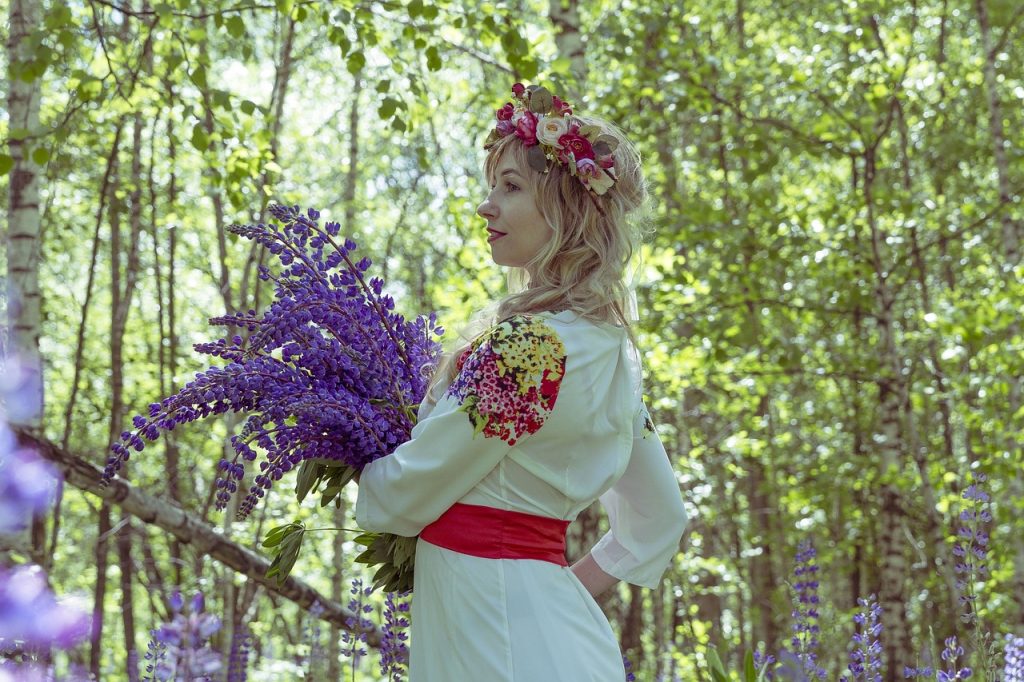 A woman in folk dress among summer birches