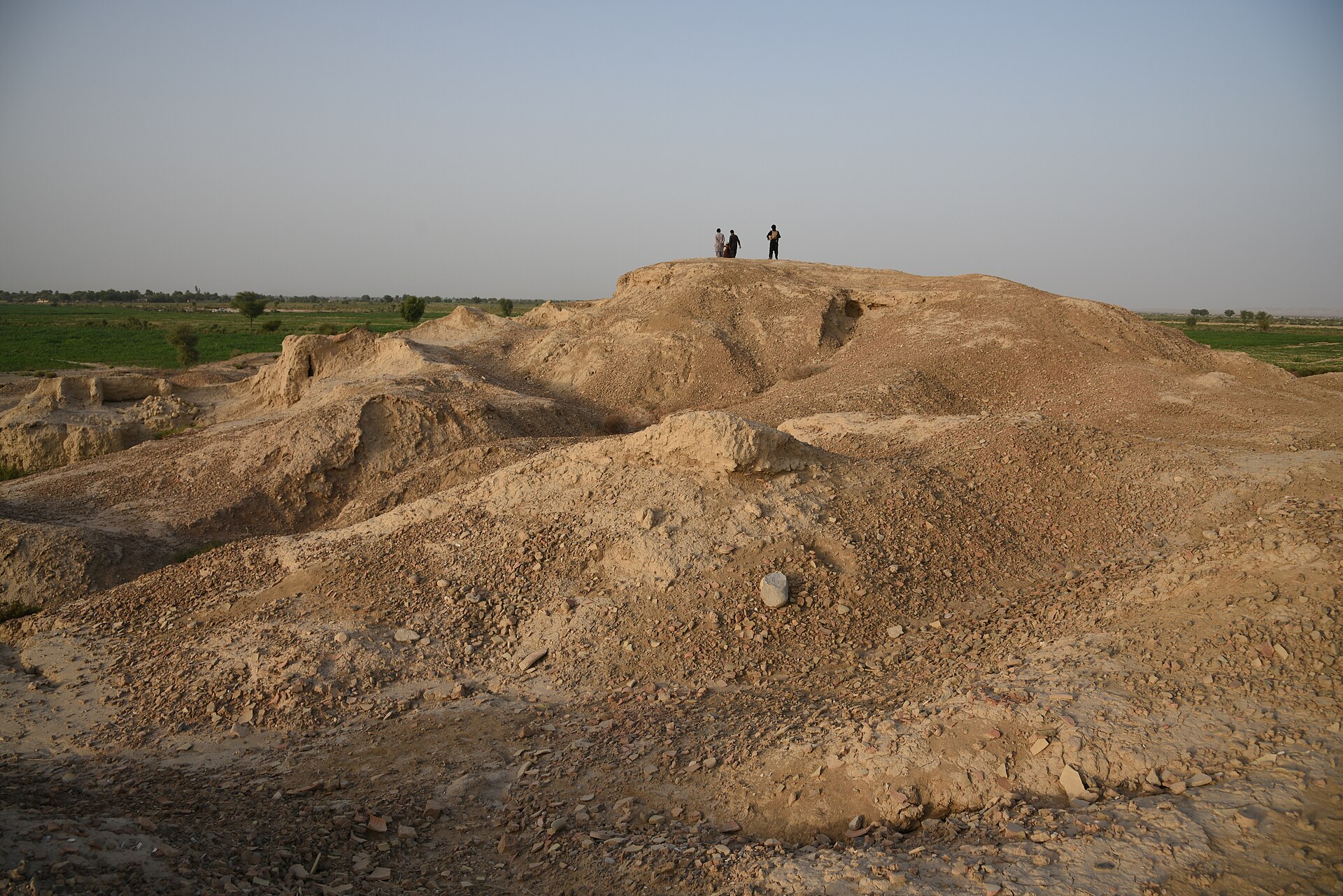 Eroded mudbrick remains poke through the ground where excavators traced thousands of years of continuous settlement.