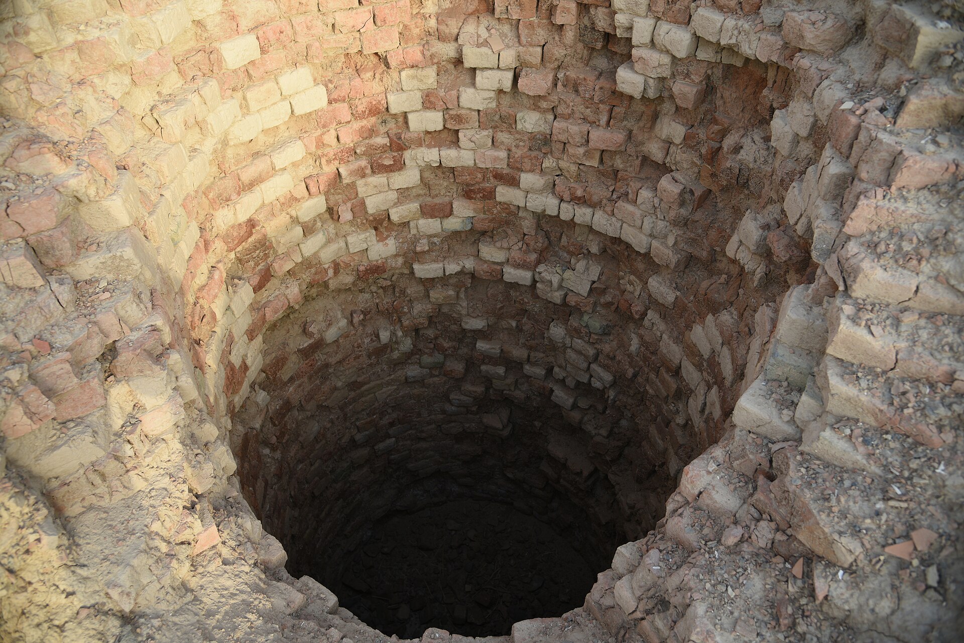 A deep well cut into the earth, evidence of the practical engineering that sustained daily life at Mehrgarh.