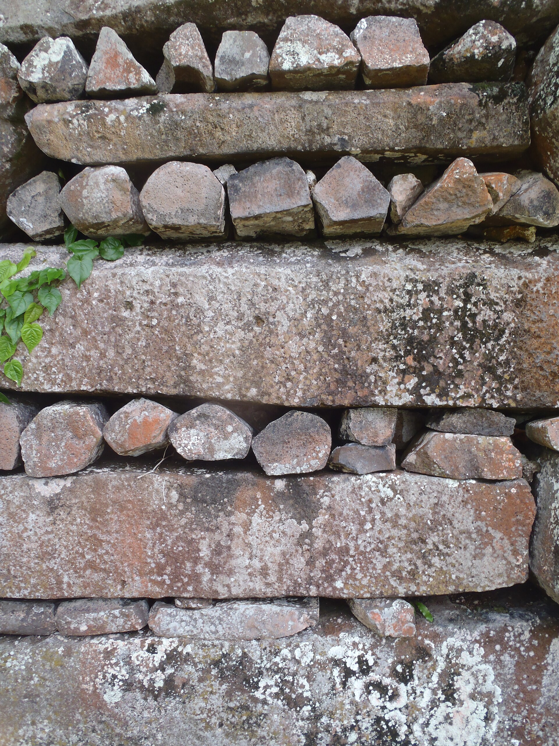 The header-and-stretcher pattern up close: long basalt columns laid in alternating directions to bind the wall together.