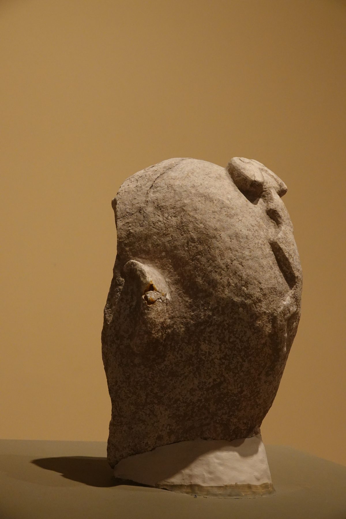 Stone statue from Nevali Cori showing a carved head with a snake on the back
