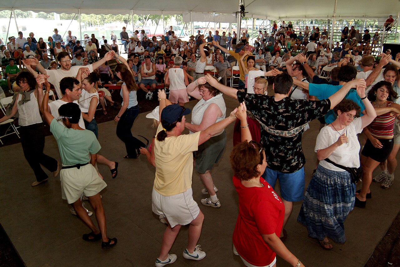 People trying Scottish ceilidh dancing at a folk festival