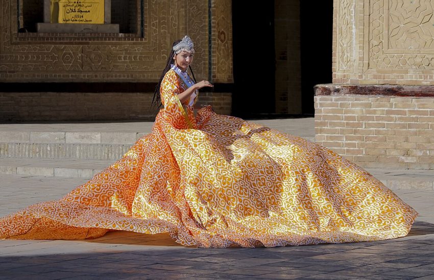 A woman in a traditional Uzbek adras dress of bright ikat silk