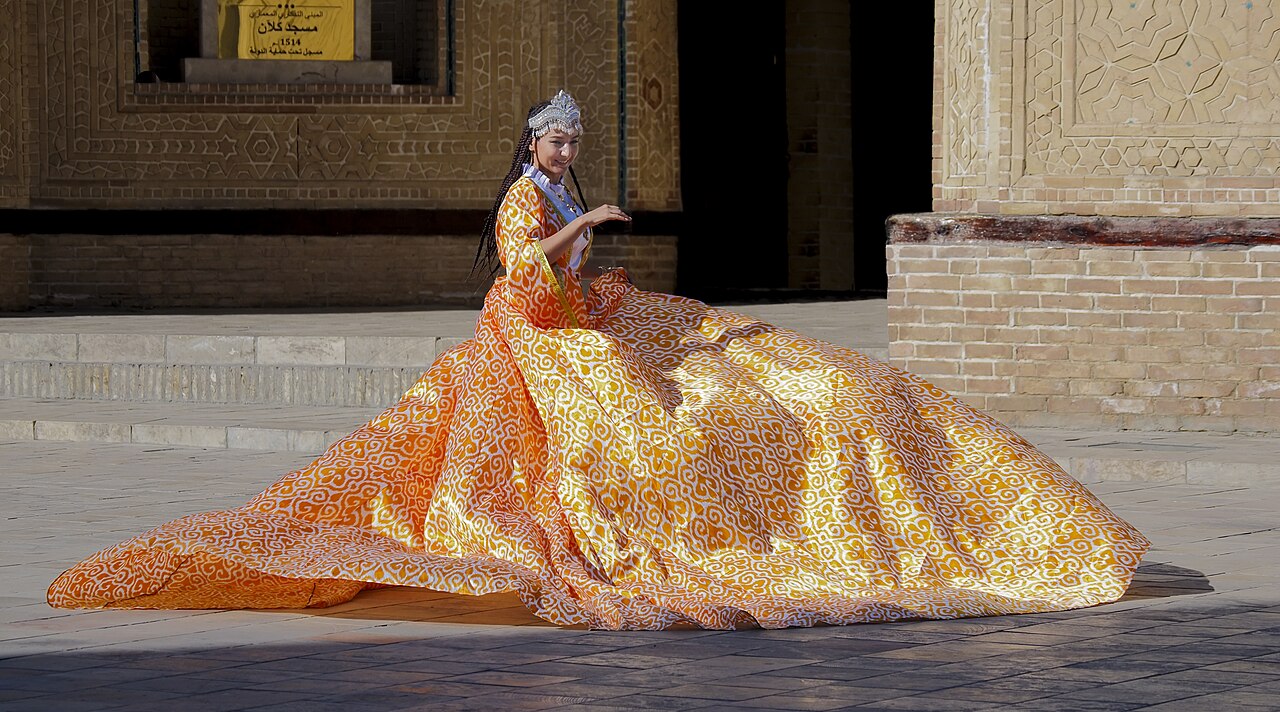 A woman in a traditional Uzbek adras dress of bright ikat silk