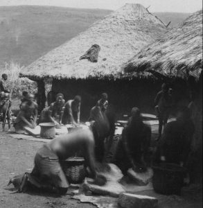 Gusii women grinding grain, a scene of daily household life.