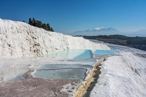 The gleaming white travertine terraces of Pamukkale below the ancient city of Hierapolis.