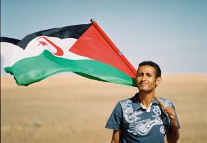 A Sahrawi with a flag; the people speak Hassaniya Arabic.