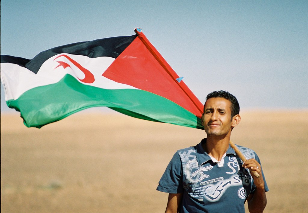 A Sahrawi with a flag; the people speak Hassaniya Arabic.