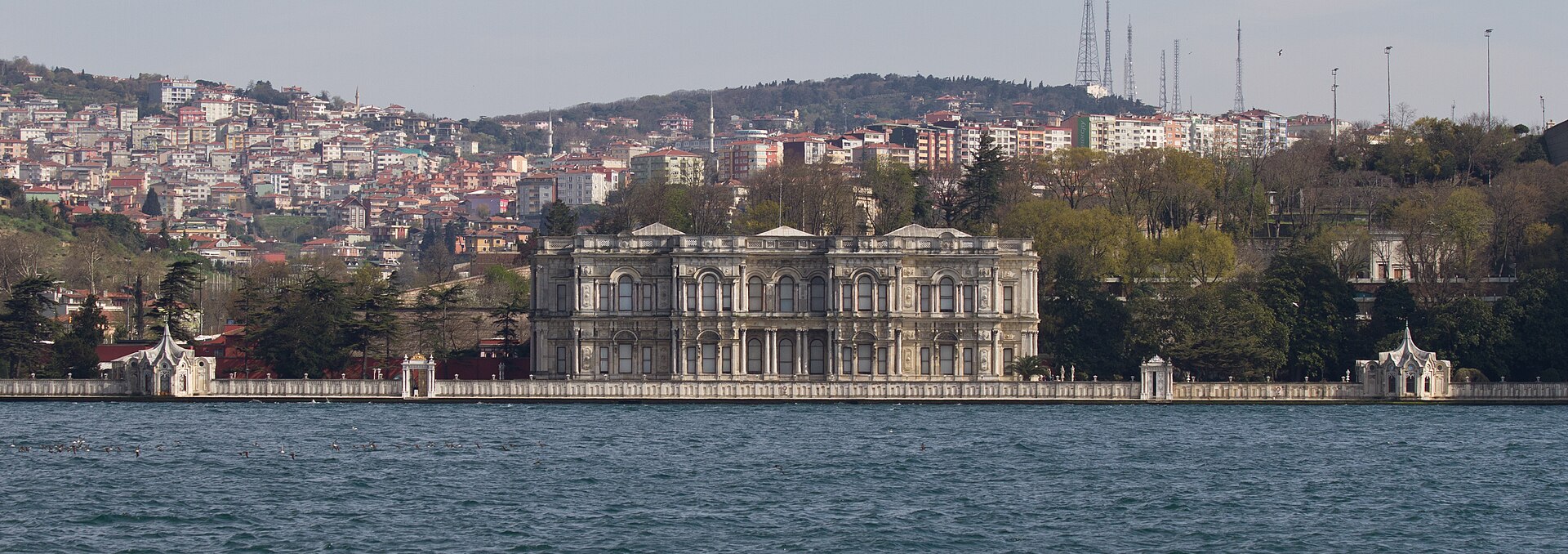The palace seen in wide view, framed by gardens rising up the hillside behind it.