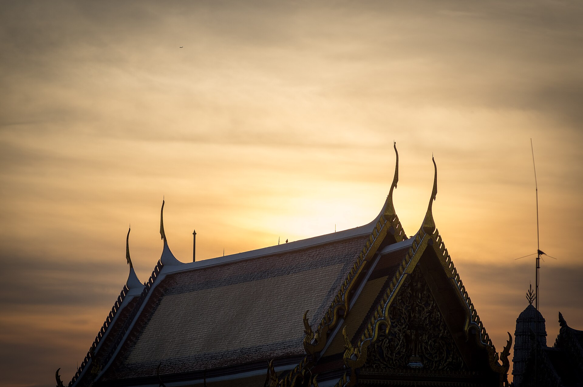 A roof of the Grand Palace at sunrise, its tiles and ornament catching the light.