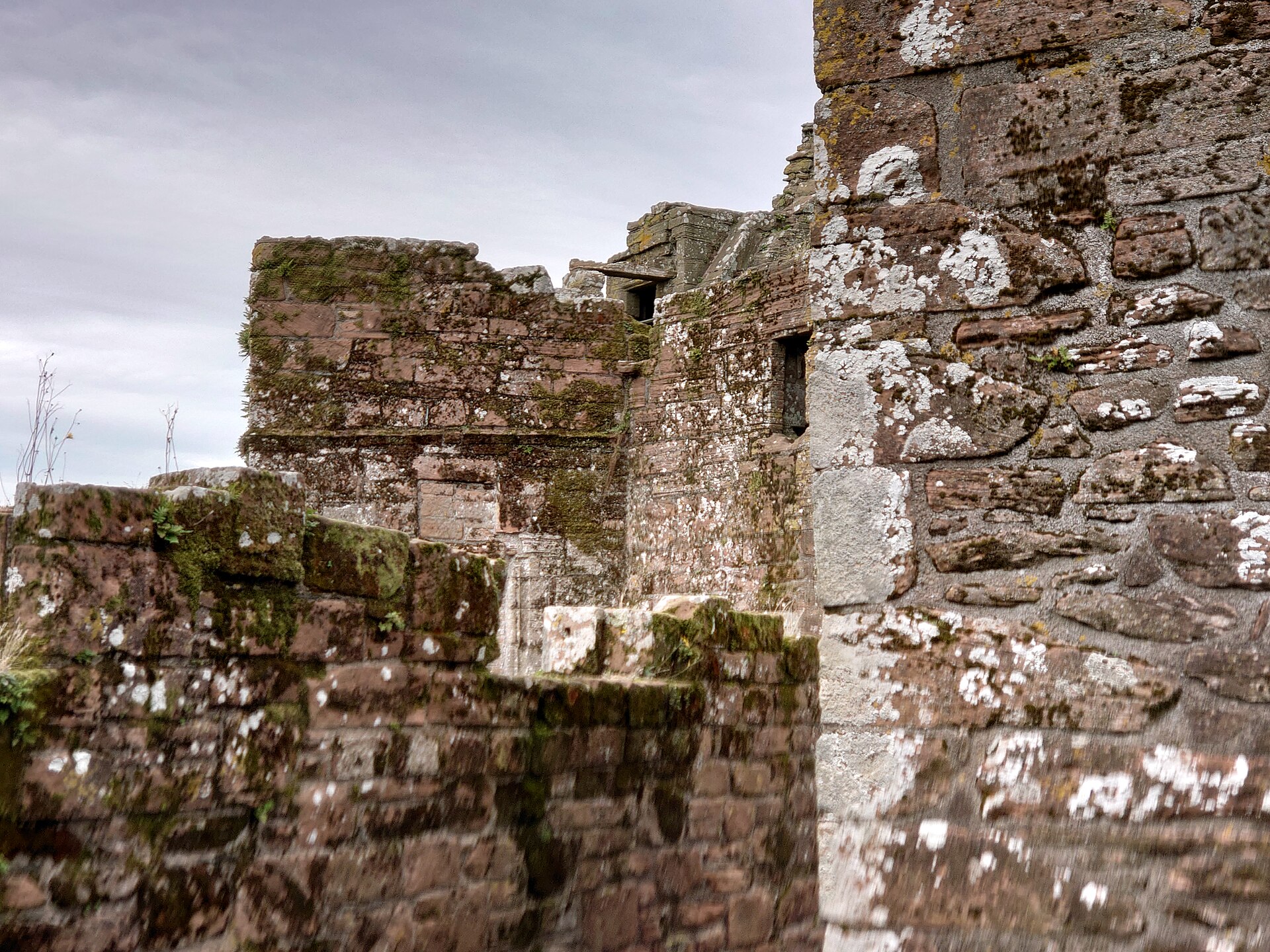 The castle's red sandstone walls reflected in the surrounding moat