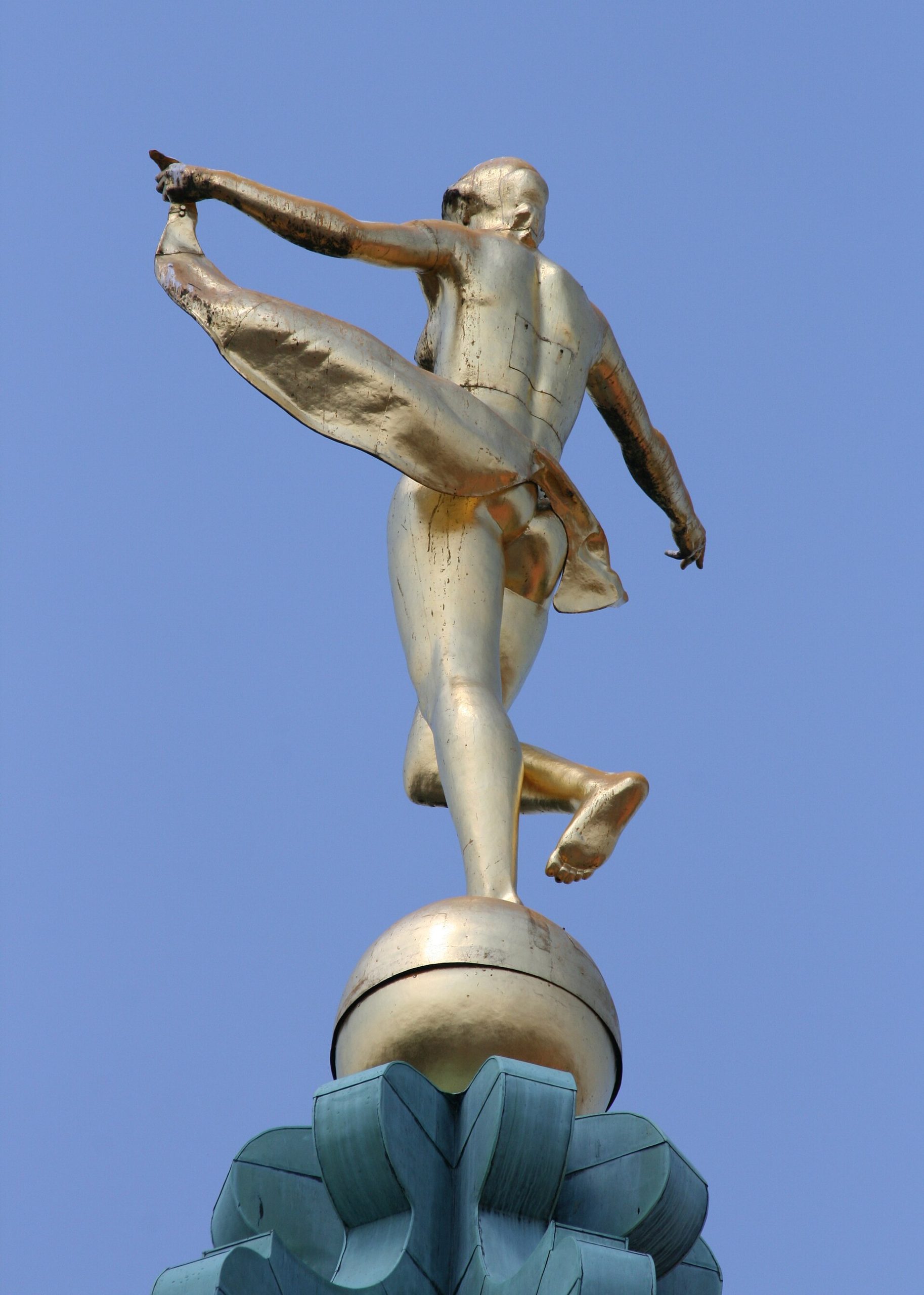 The gilded figure of Fortuna turning as a weathervane atop the palace dome