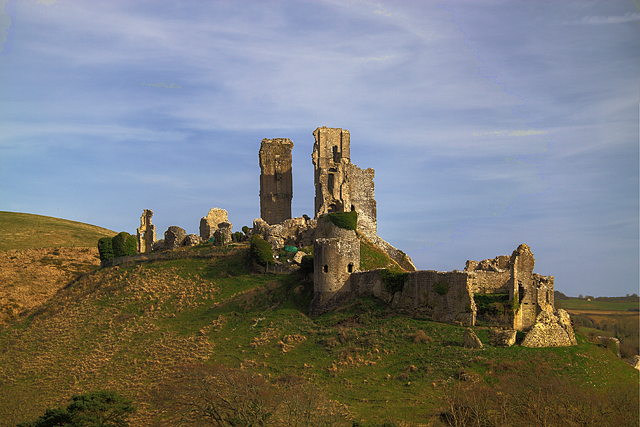 Corfe Castle standing on its steep natural hill, guarding a gap in the Purbeck ridge in Dorset