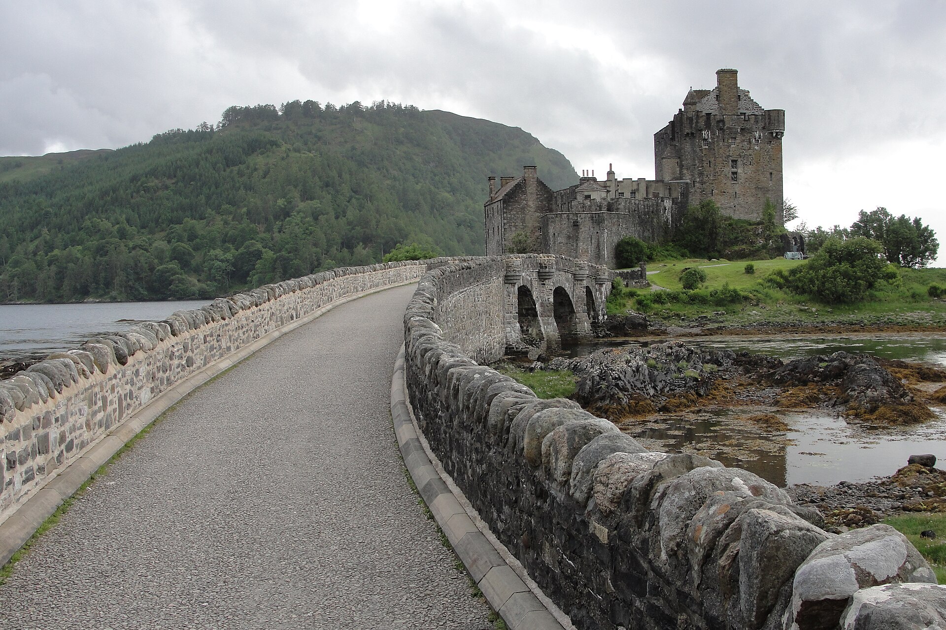 The arched stone footbridge that links the castle island to the mainland, added in the twentieth-century restoration